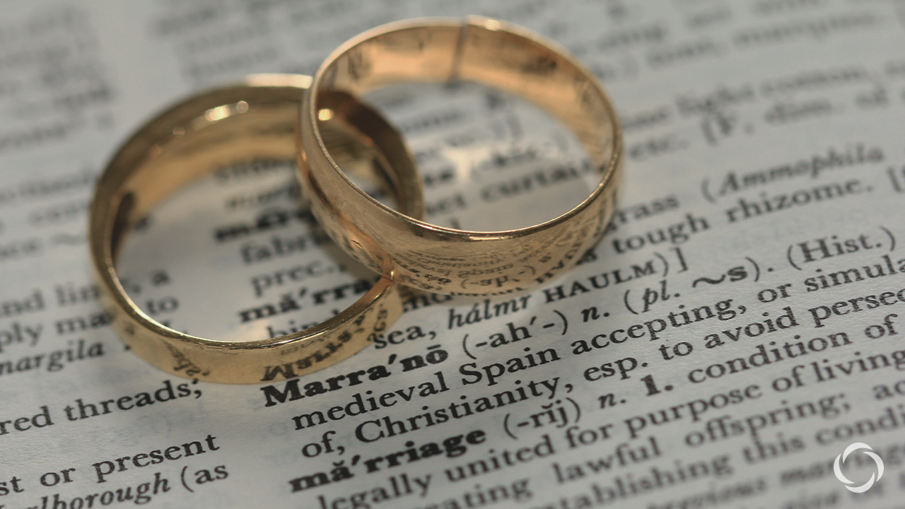 Two wedding rings on top of scripture
